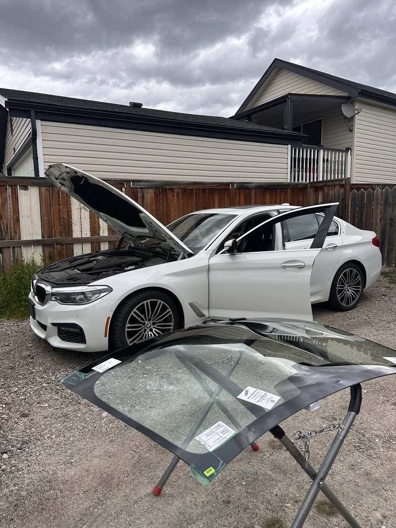 BMW 5 Series. Old glass out, new glass waiting, cowl and hood protected.